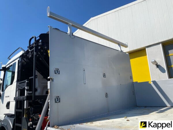 LKW mit hydraulischem Kran vor Industriegebäude bei Kappel, klarer Himmel im Hintergrund.
