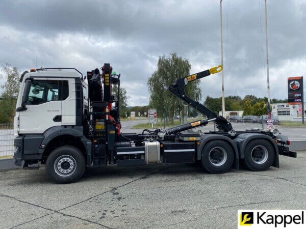 Großer LKW mit Kran in Industriegebiet, ideal für Transport- und Bauaufgaben. Effizienter Containerumschlag.