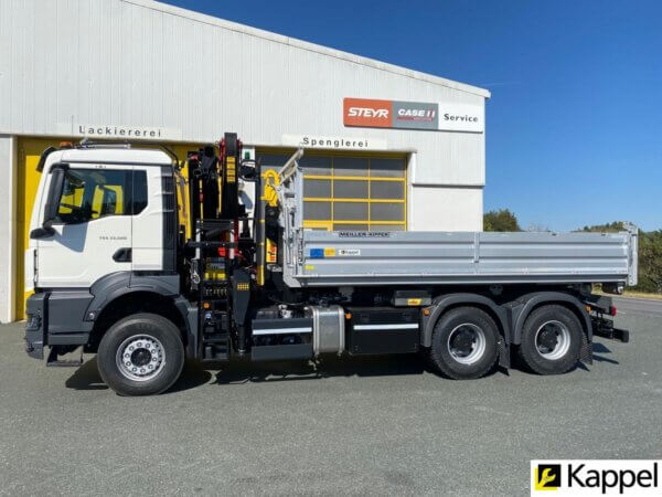 Lkw mit Kran vor Werkstattgebäude, Meiller-Kipper, bei Kappel, sonniger Tag, Bauzubehör im Hintergrund.