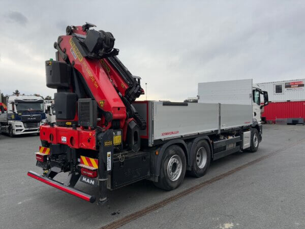 LKW mit Ladekran von Palfinger und Auflieger von Schwarzmüller auf einem Parkplatz vor MAN Service Station.