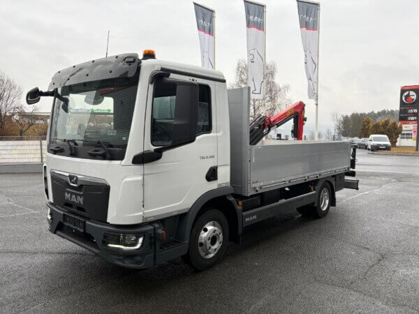 MAN LKW mit Kran auf Parkplatz, umgeben von Fahnen. Ideal für Transportaufgaben bei jedem Wetter.