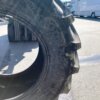 Großer, gebrauchter Continental-Reifen auf einem sonnigen Parkplatz neben einem weißen Fahrzeug.