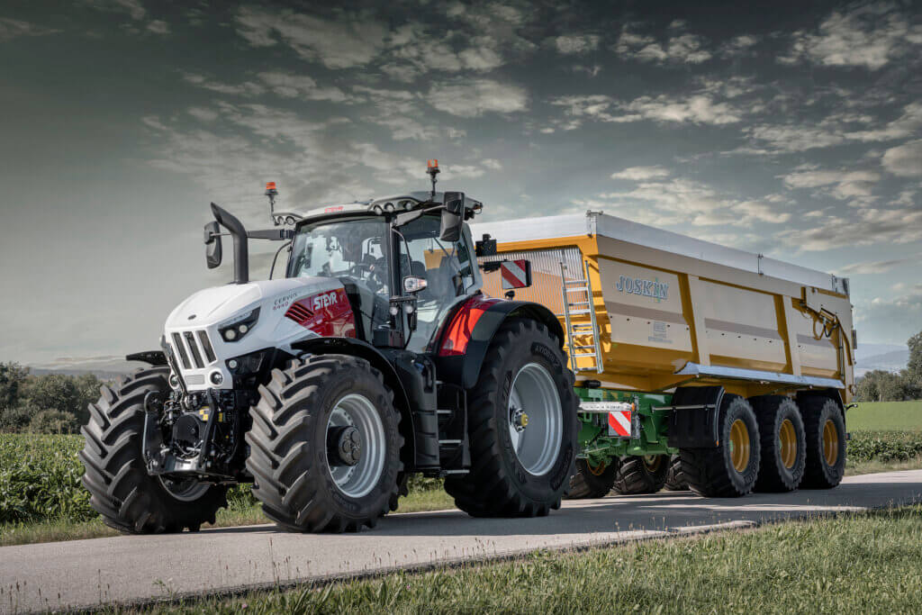 Moderner Traktor mit Joskin-Anhänger auf einer Landstraße, ideal für landwirtschaftliche Arbeiten.