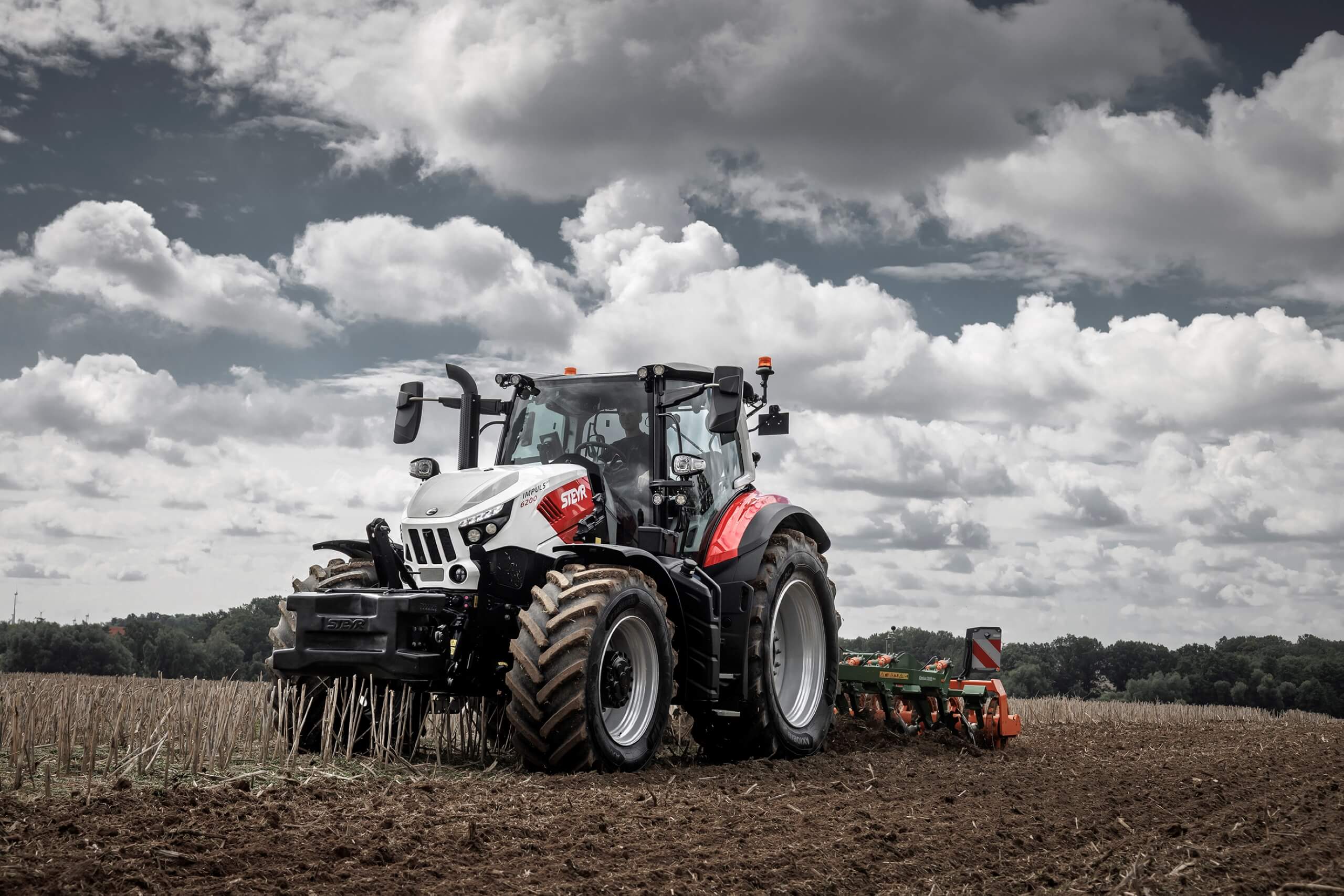 Moderner Traktor auf einem Acker unter bewölktem Himmel bei der Feldarbeit. Effiziente Landtechnik in Aktion.